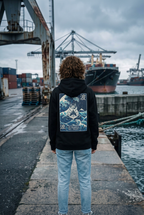 GataKarma Marea Hoodie, worn with the hood down in an industrial harbour (2/3) — MAREA collection by BarnaBorders