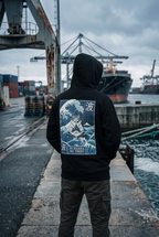 GataKarma Marea Hoodie, worn with the hood up in an industrial harbour (3/3) — MAREA collection by BarnaBorders